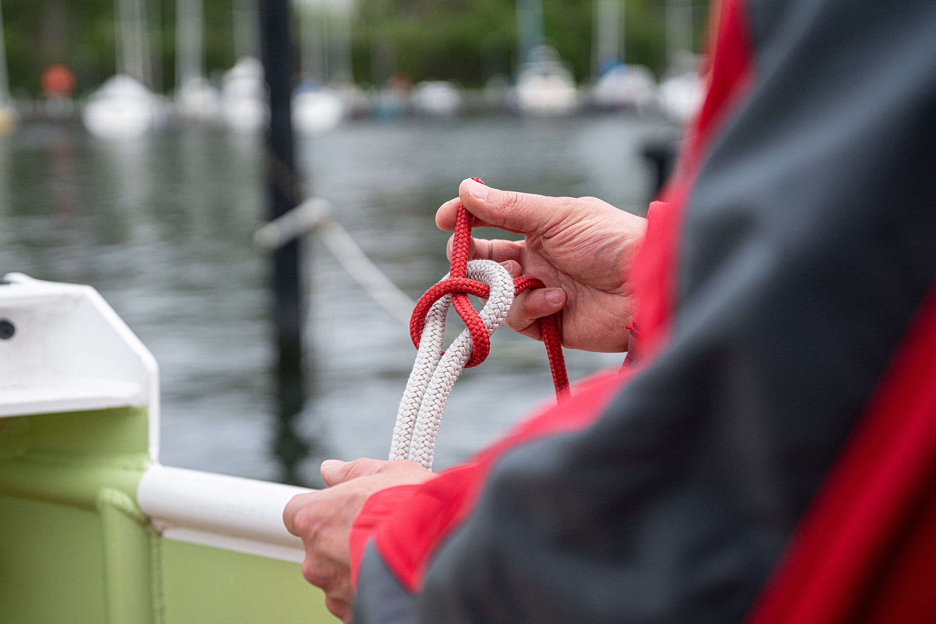 An Bord eines Seenotrettungsbootes knotet ein Seenotretter mit zwei Leinen einen Schotstek-Knoten.
