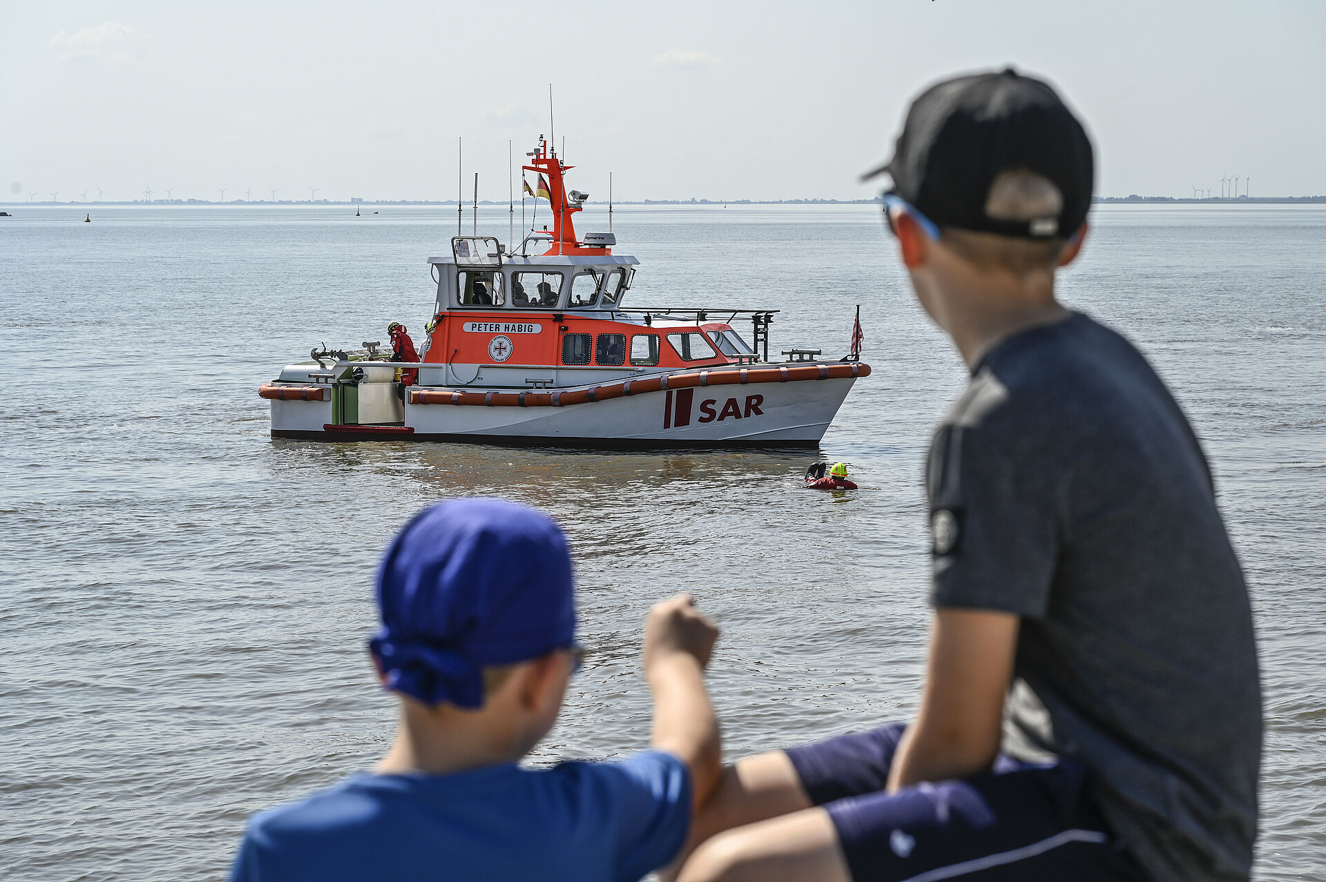 Zwei Kinder beobachten eine Übung der Seenotretter mit einem Seenotrettungsboot