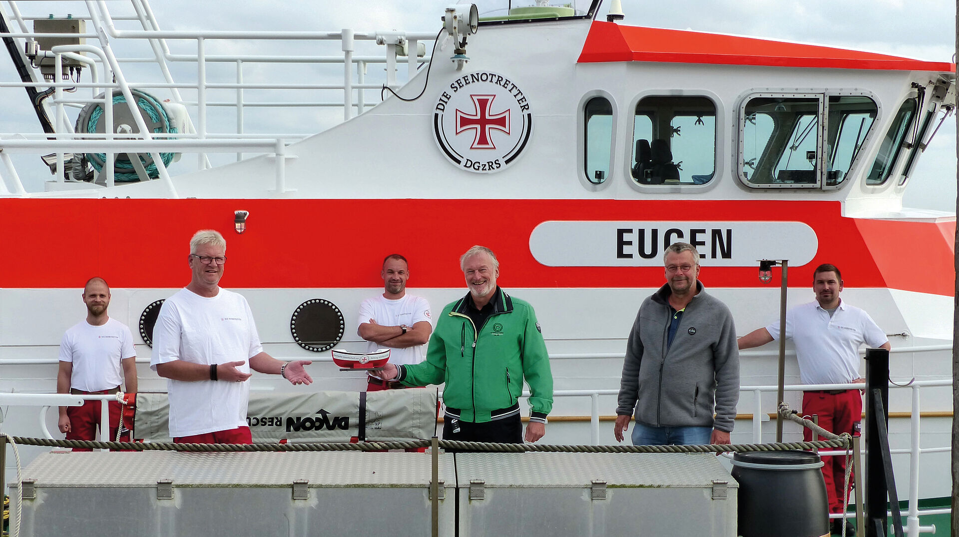 Seenotretter überreichen Männern aus Norderney ein Miniatur-Seenotretterschiff auf der EUGEN