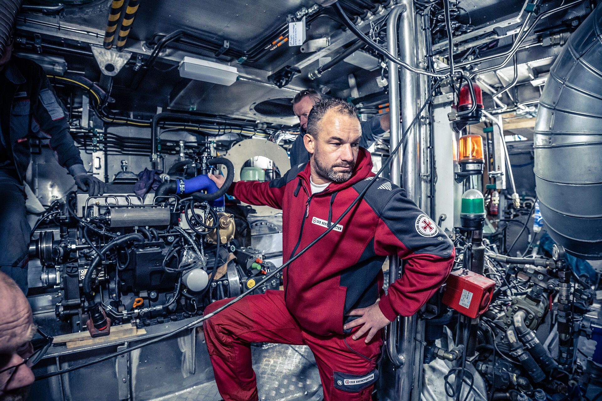 Im Maschinenraum des Seenotrettungskreuzers EUGEN steht Vormann Heiko Erdwiens gemeinsam mit Werftmitarbeitern zwischen der Technik für den Antrieb.