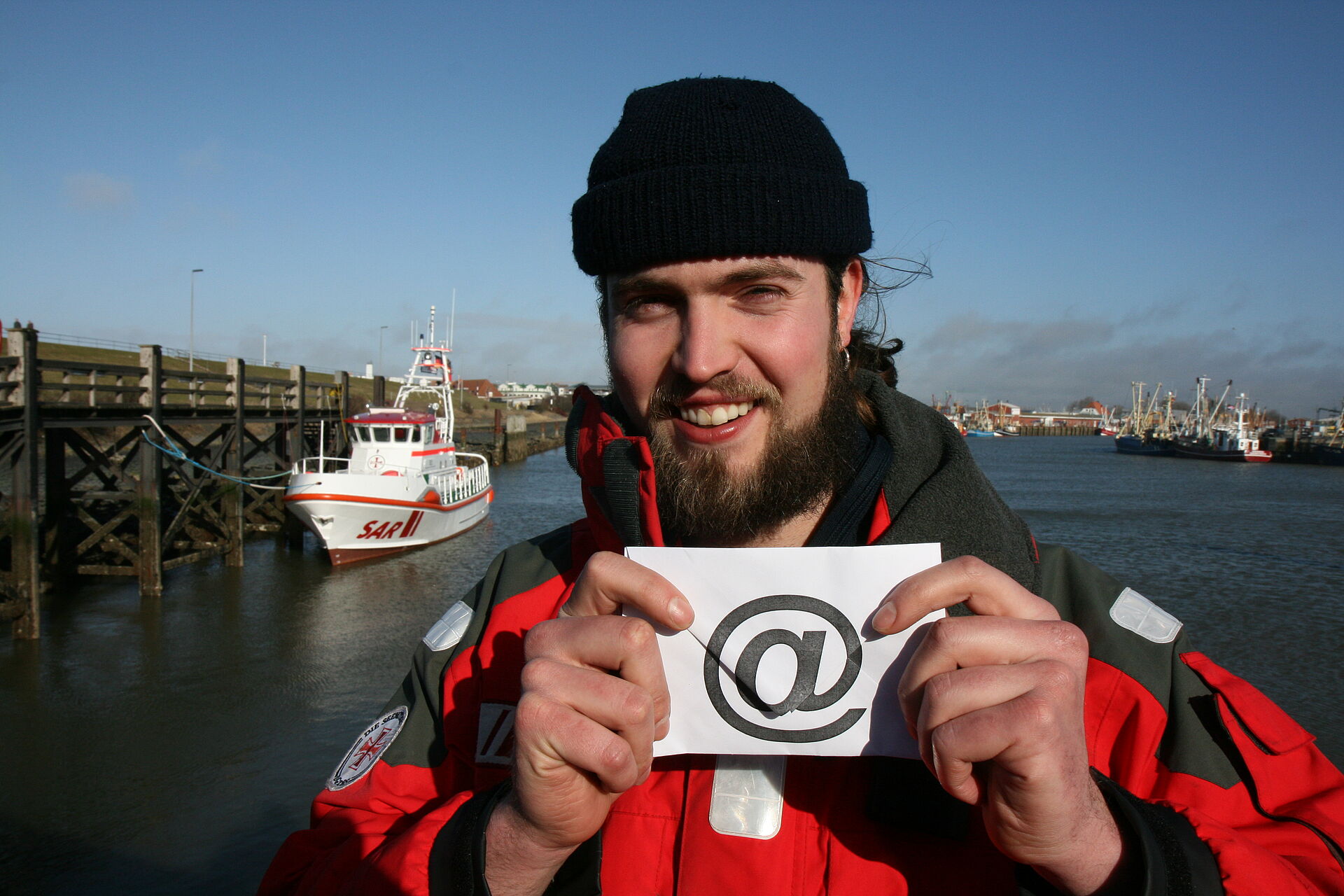 A rescuer in the harbour shows an envelope with an at-sign