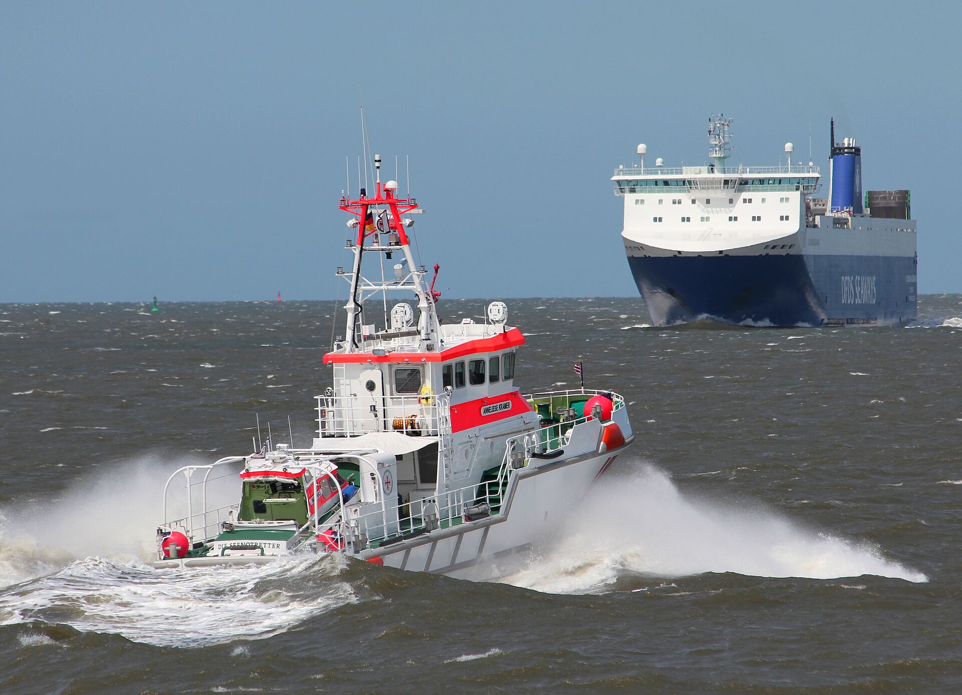 Seenotrettungskreuzer fährt auf großes Containerschiff zu