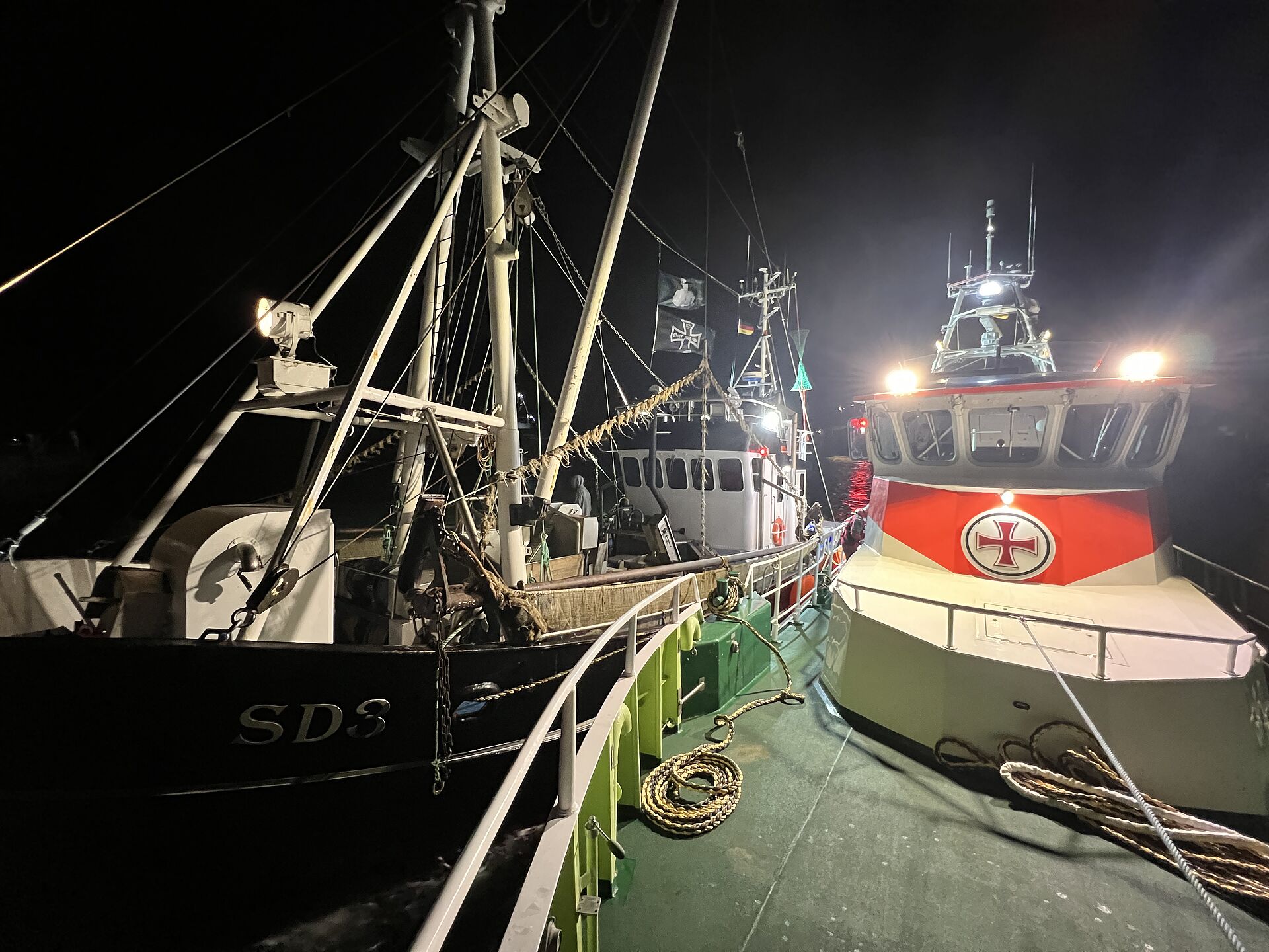 Ein Seenotrettungskreuzer hat bei Nacht einen Fischkutter längsseits in Schlepp genommen