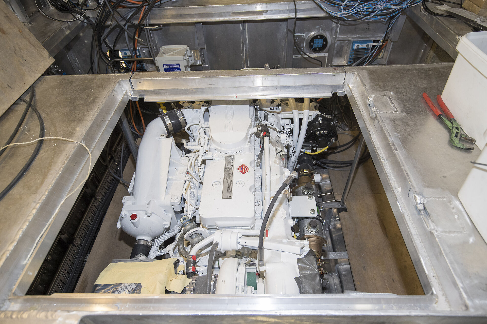 Blick von oben auf den weißen Bootsmotor, der eingebaut im Maschinenraum eines Seenotrettungsbootes in der Bauwerft ist.