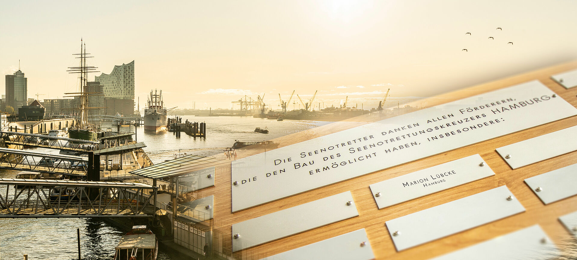 Eine Holztafel mit Aluminium-Schildern mit Namen von Spendern. Im Hintergrund die Silhouette des Hamburger Hafens.