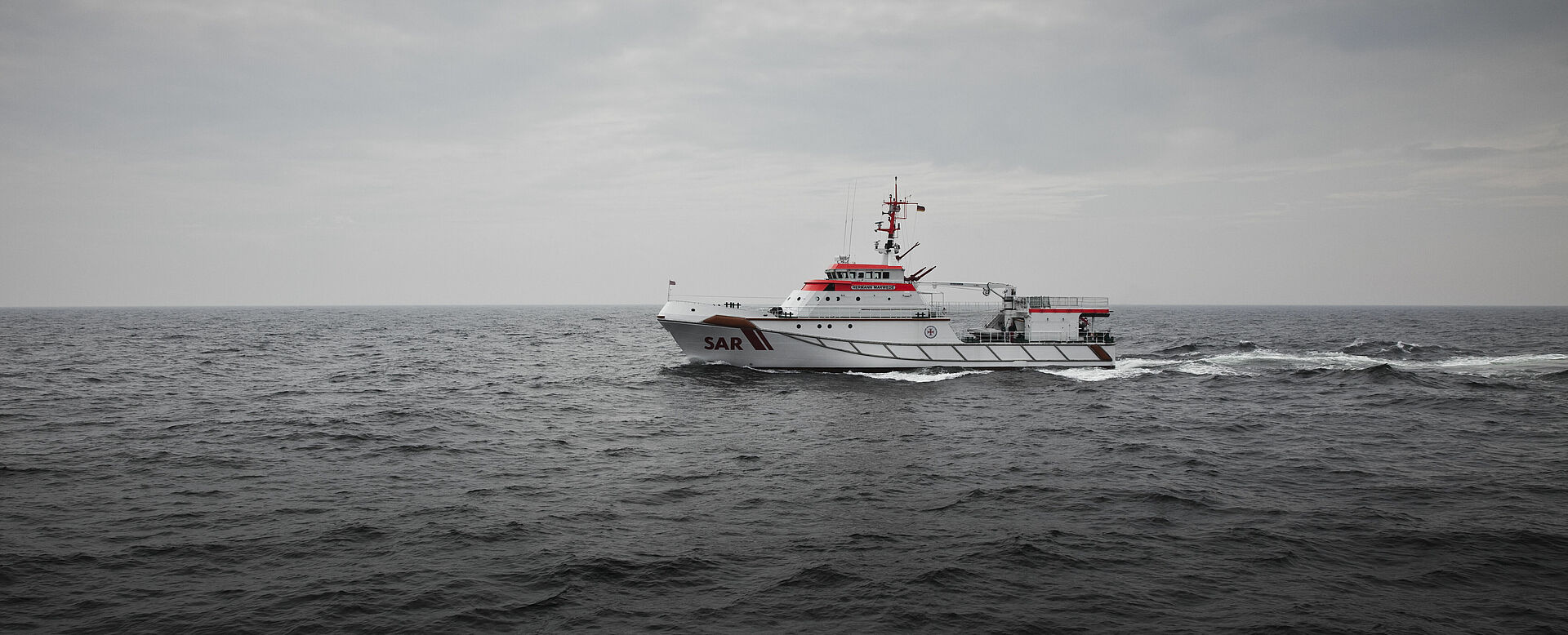 Der Seenotrettungskreuzer fährt in mittlerer Fahrt bei trübem Wetter druch die Nordsee.