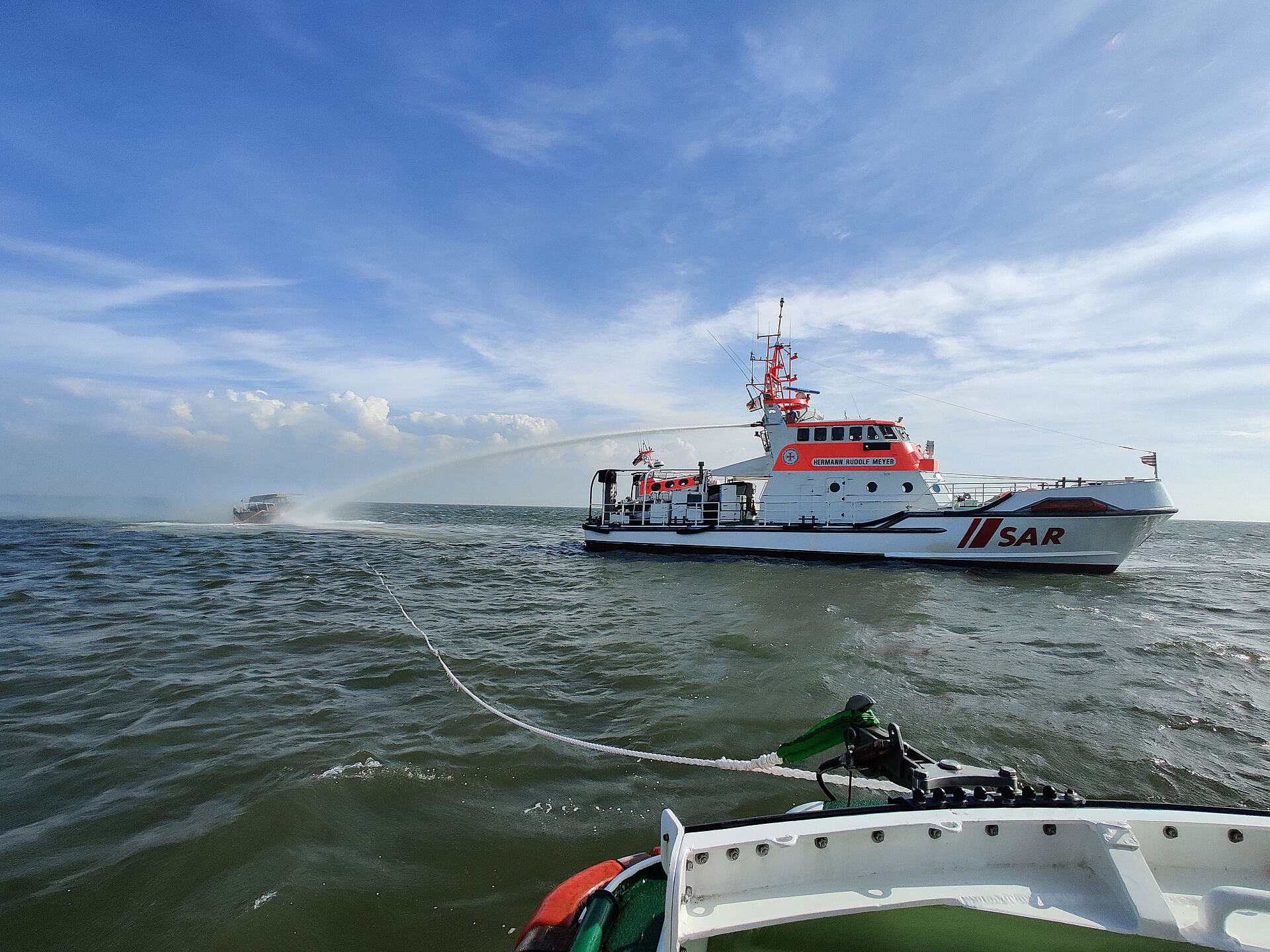 Seenotrettungskreuzer löschen brennende Yacht auf hoher See
