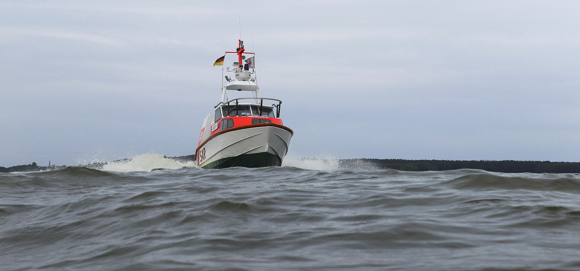 Das Seenotrettungsboot fährt in schneller Fahrt auf flachem Wasser.