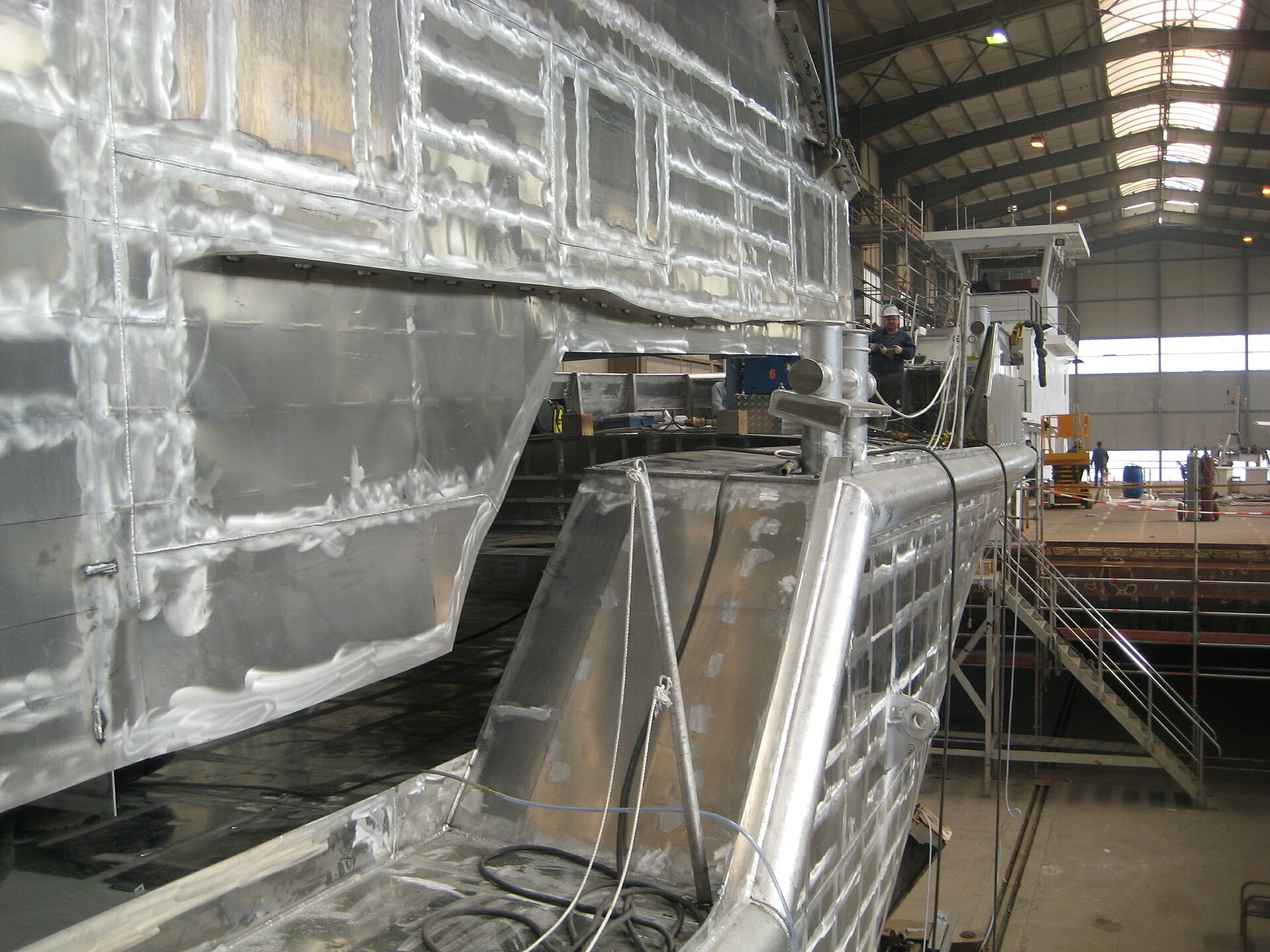 Das Deckshaus aus Aluminium wird von einem Hallenkran auf den Aluminium-Rumpf des Rohbaus des Seenotrettungskreuzers gehoben.