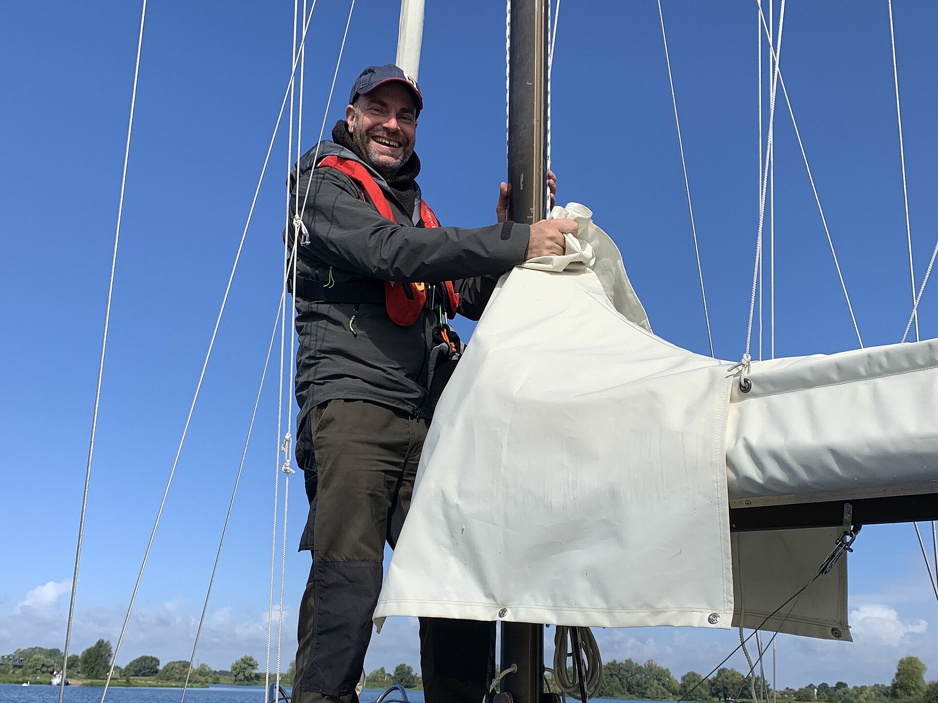 Mark Eichberger steht an Bord seines Segelbootes am Segelmast.