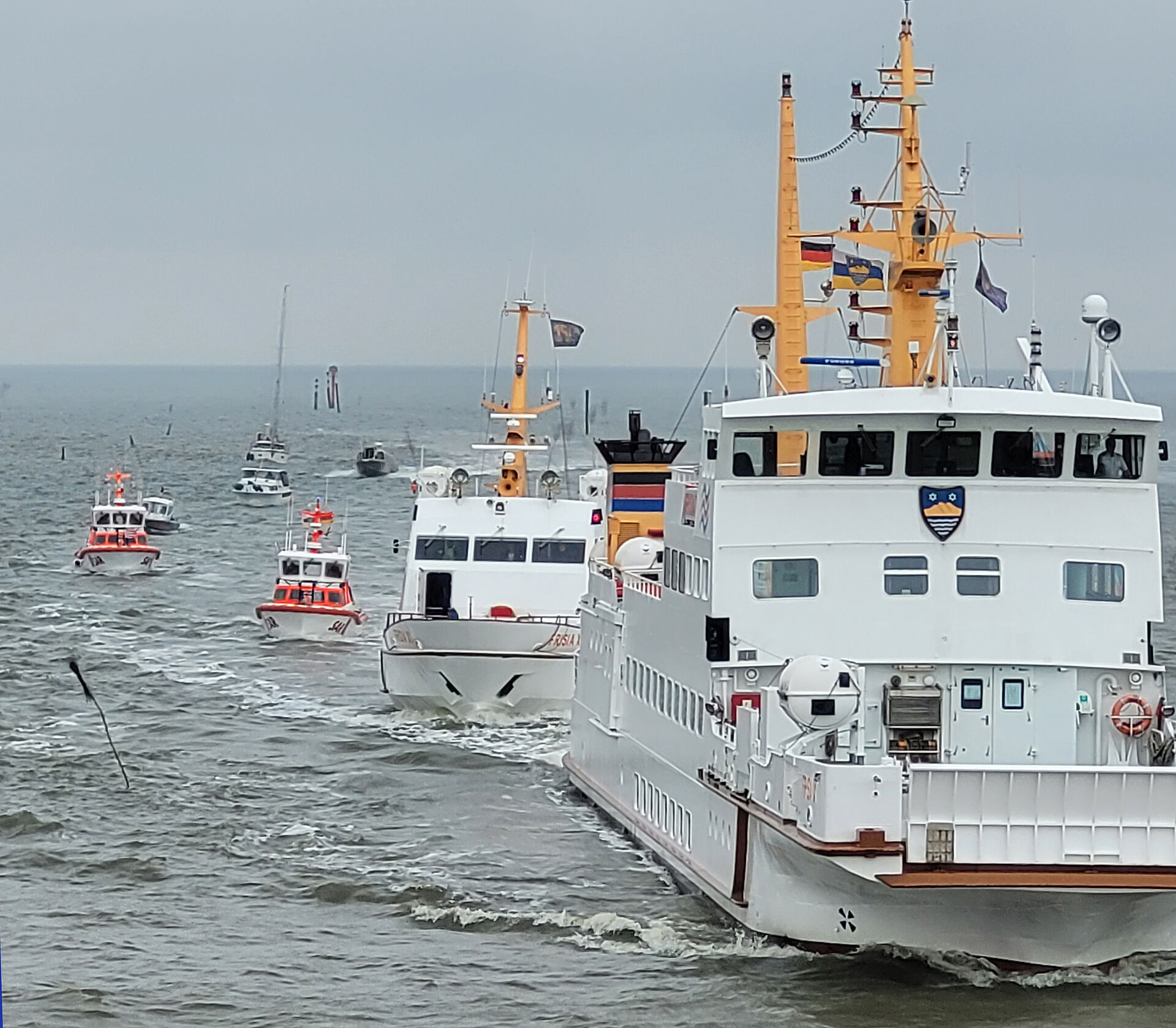 Inselfähre führt Flotte von kleinen Booten und Schiffen samt Seenotrettungskreuzer vor Juist an
