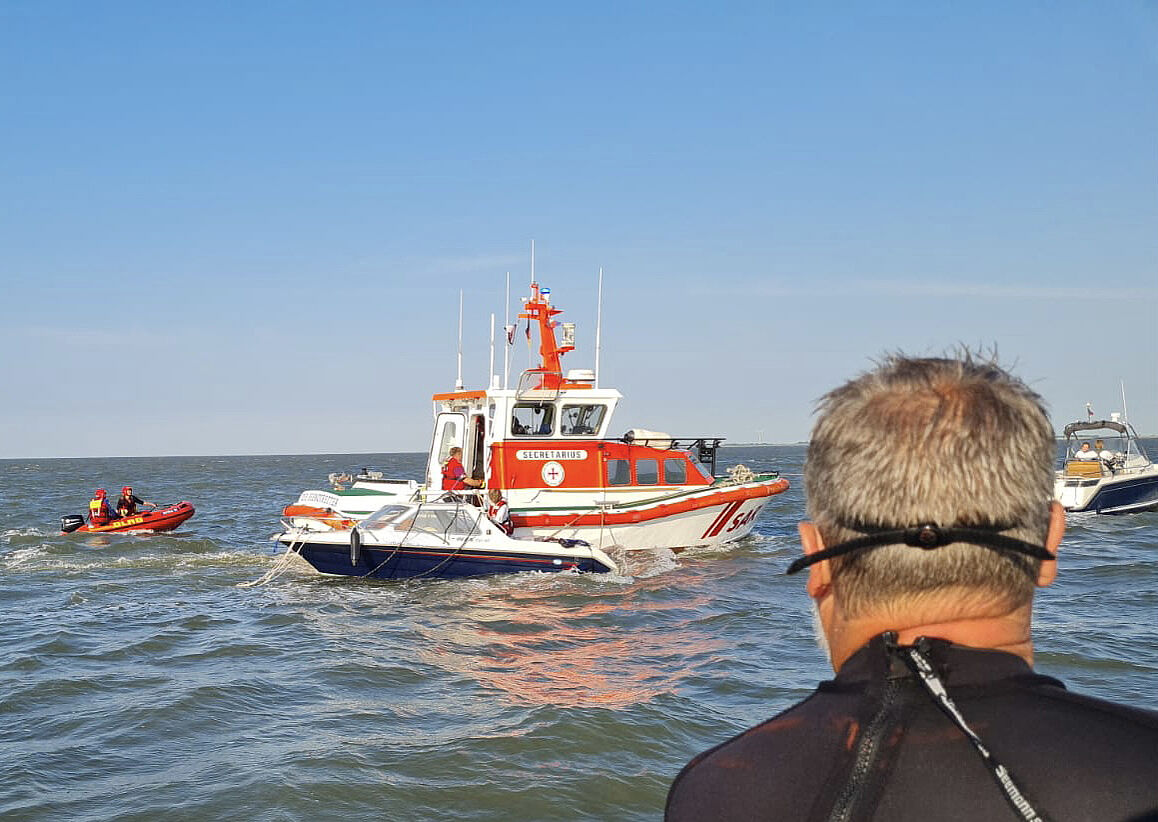 Gemeinsamer Rettungseinsatz auf See der DGzRS und DLRG für ein Motorboot; das Seenotrettungsboot SECRETARIUS der DGzRS hat ein Motorboot längsseits genommen, im Hintergrund ist ein Schlauchboot der DLRG zu sehen und im Vordergrund der Hinterkopf eines Menschen