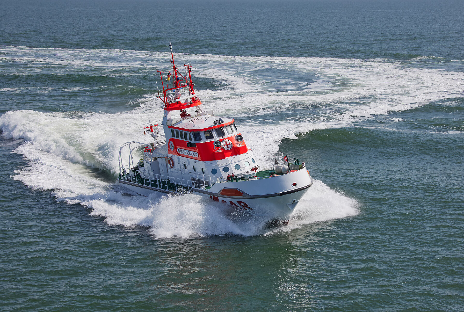 Der Seenotrettungskreuzer HANS HACKER fährt in schneller Fahrt auf der Nordsee bei sonnigem Wetter.
