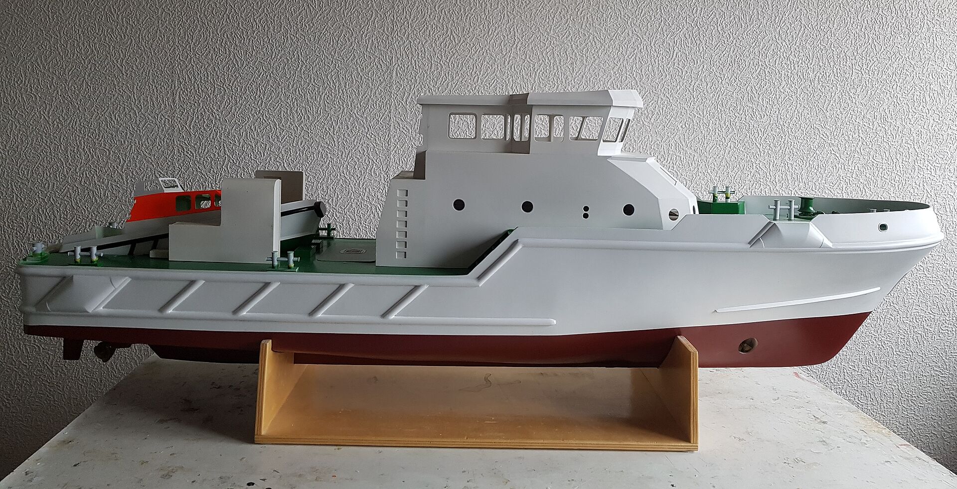 Ein Modell eines Seenotrettungskreuzers der DGzRS steht auf einem Holzständer. Es ist noch grau.