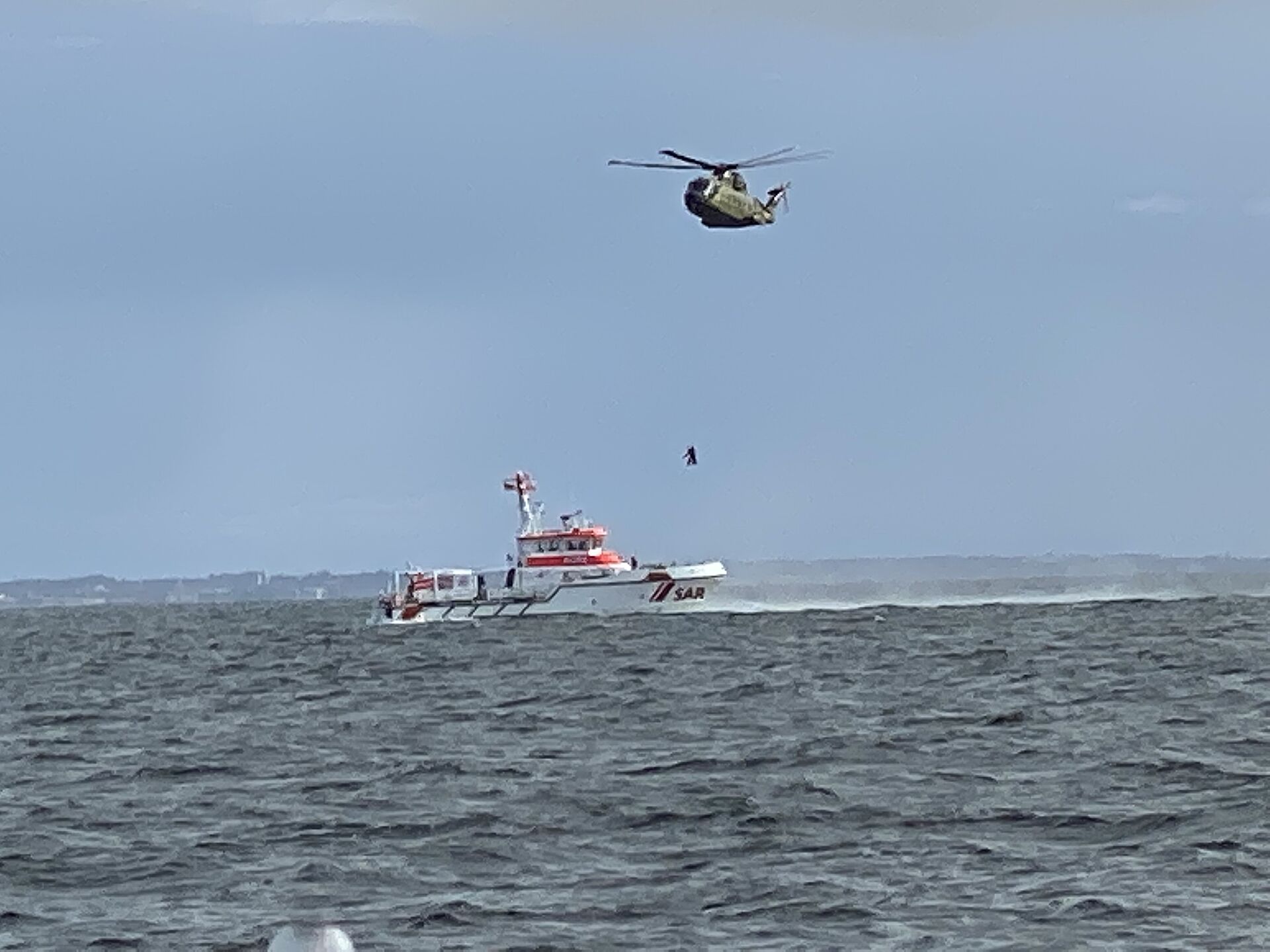 Hubschrauber schwebt ueber Seenotrettungskreuzer