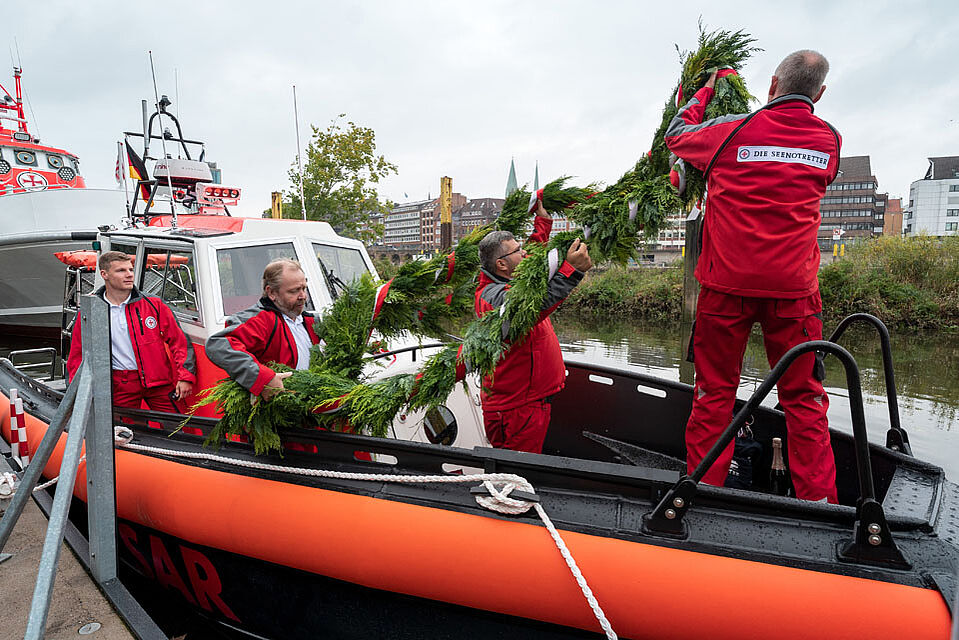 Seenotretter ziehen Blumenkranz auf das Deck ihres Bootes
