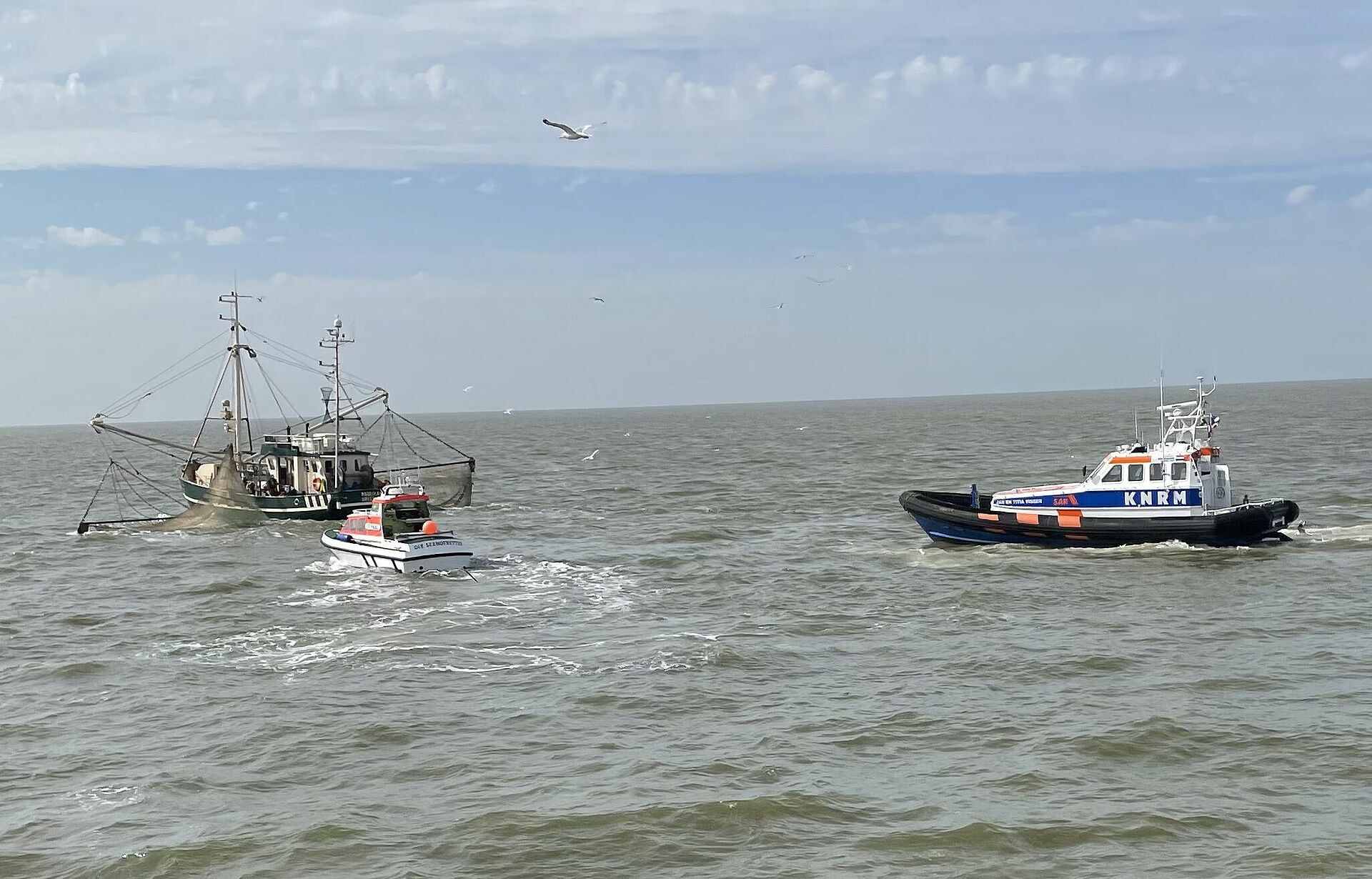 Zwei Seenotrettungsboote nähern sich auf der Nordsee einem Fischkutter.