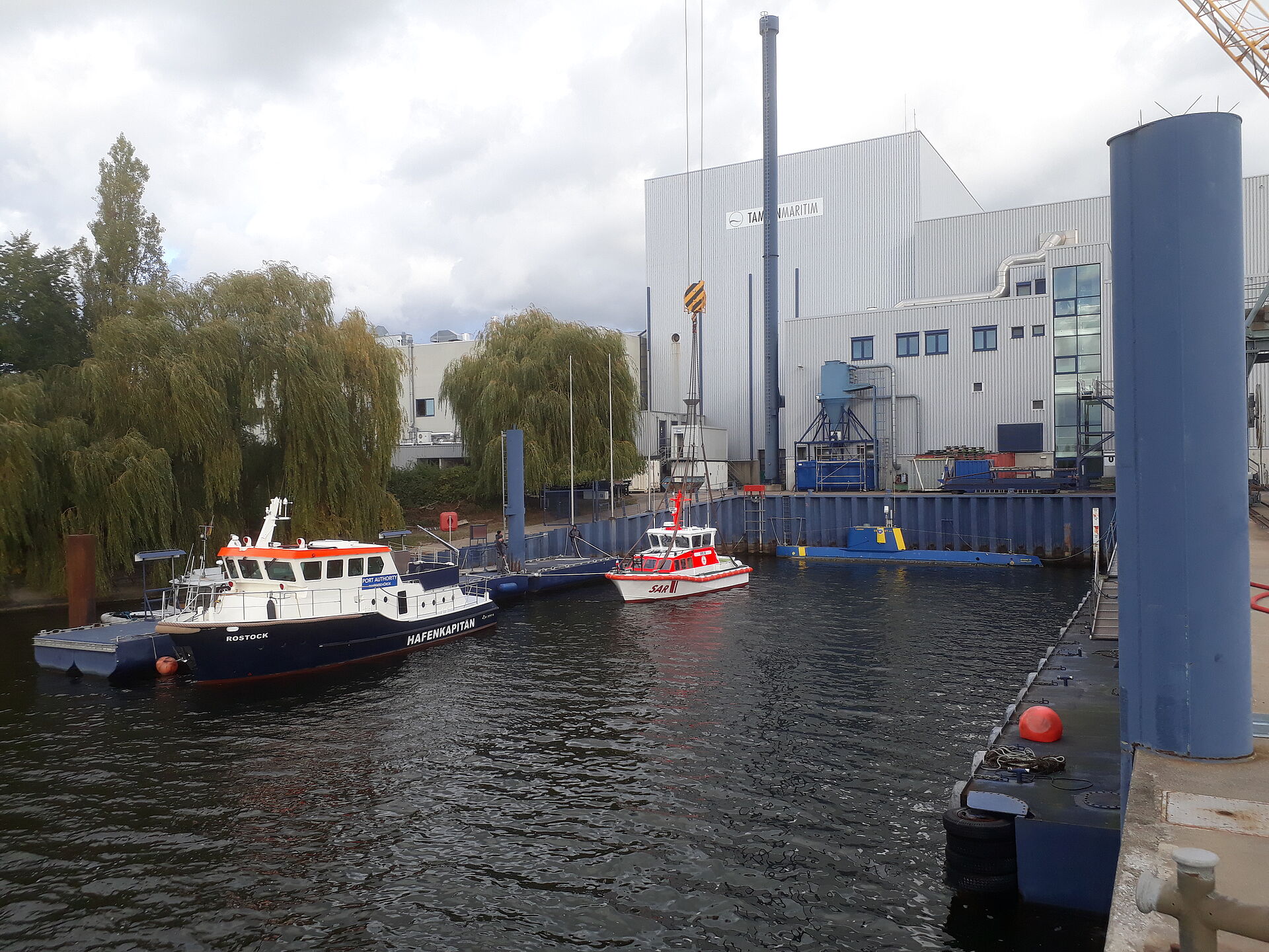 Das Seenotrettungsboot liegt im kleinen Hafenbecken der Werft. Dahinter sind die großen Hallen der Werft zu sehen.
