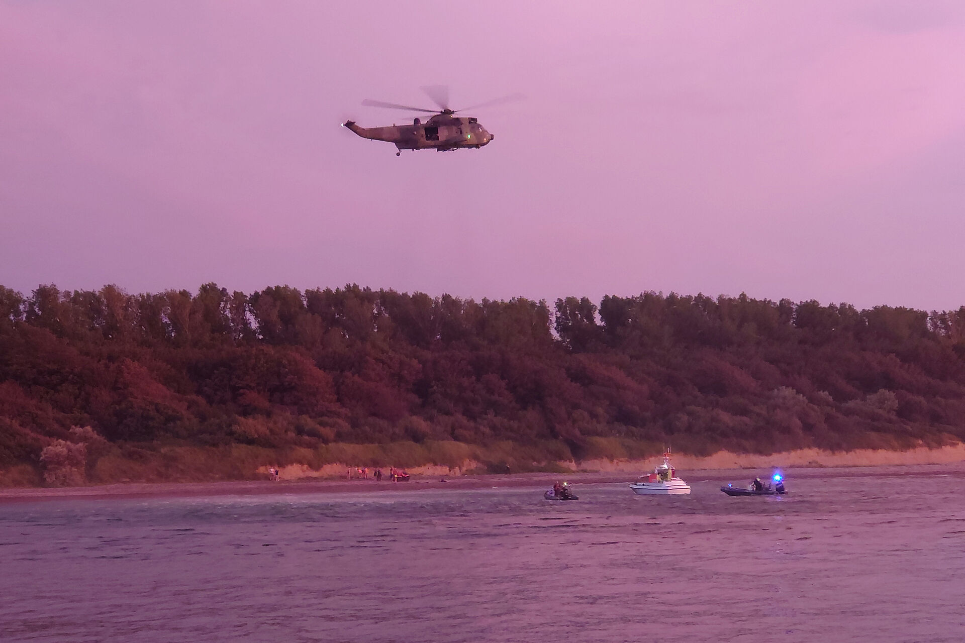 Ein Marinehubschrauber, ein Tochterboot der Seenotretter und zwei Schlauchboote suchen vor einer Steilküste die Küste ab