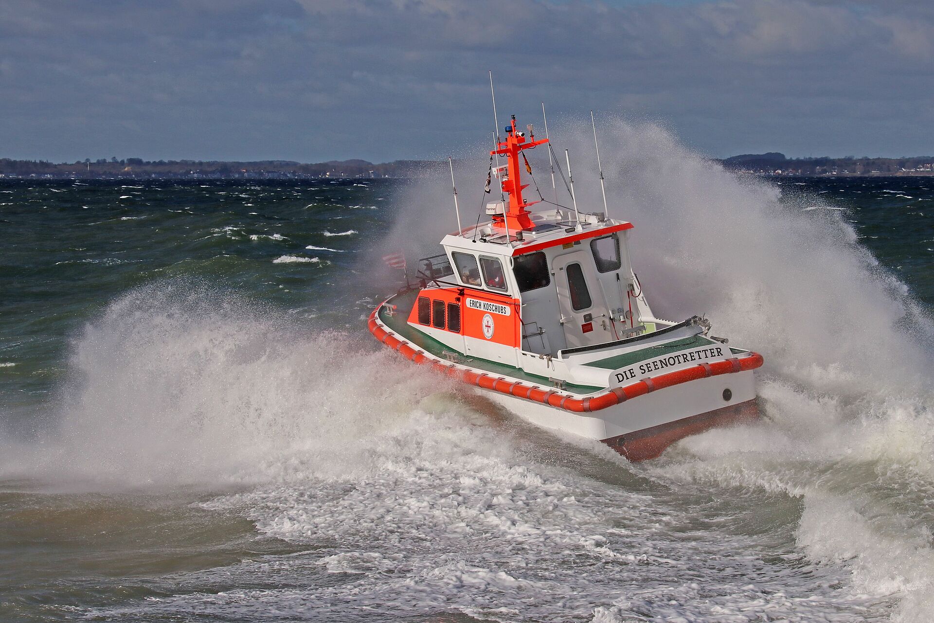 Das Seenotrettungsboot ERICH KOSCHUBS fährt durch die aufgewühlte Ostsee. Wellen schlagen Gischt.