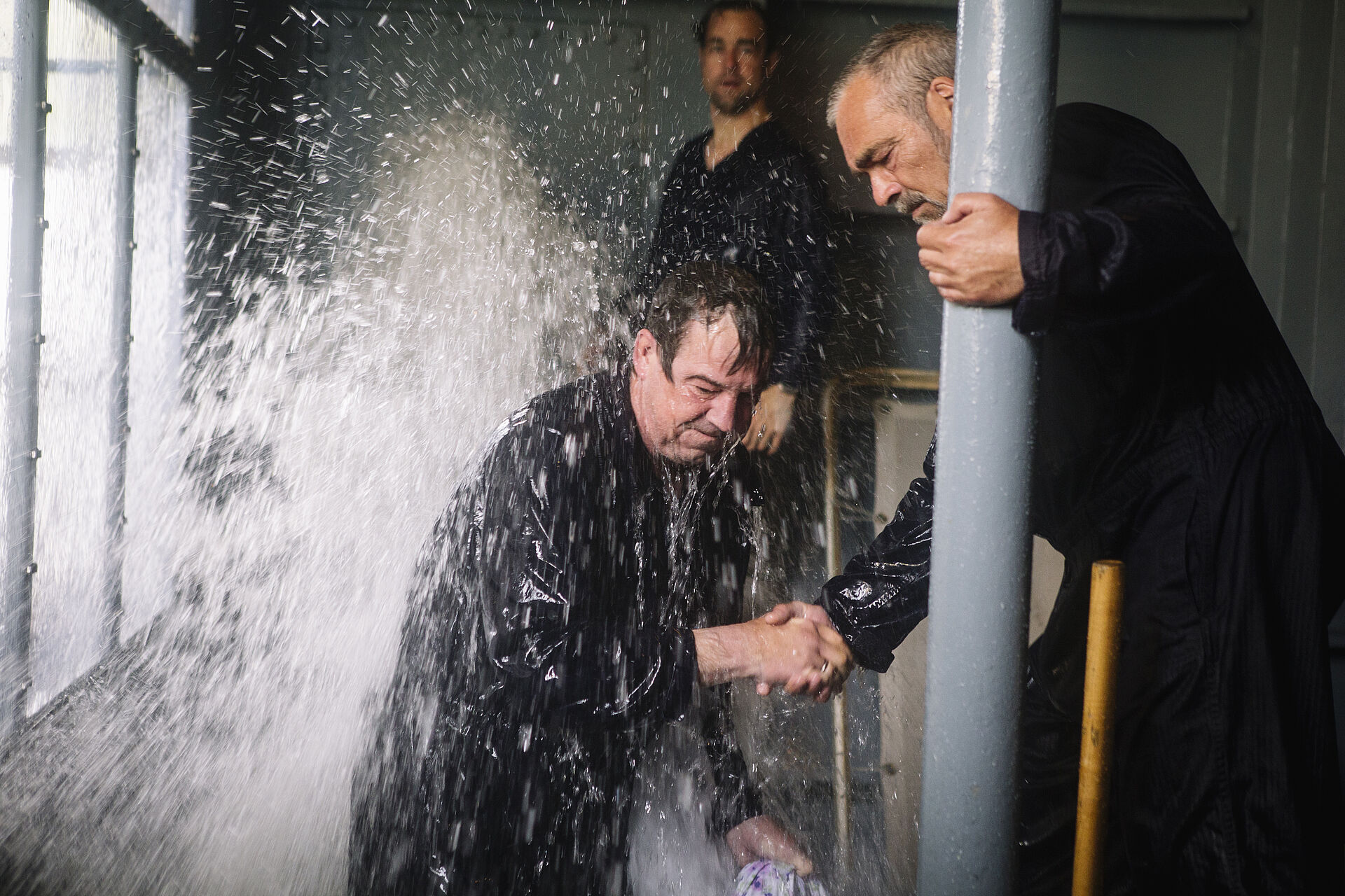 Zwei Männer versuchen ein Leck zu stopfen, aus dem Wasser spritzt.