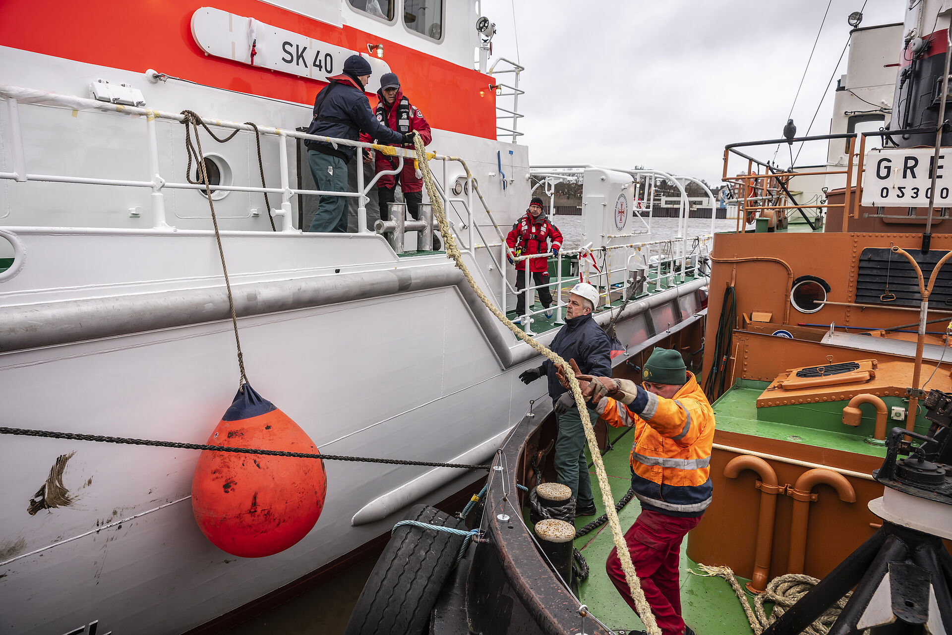 Seenotretter reichen vom Seenotrettungskreuzer eine Leine an ein anderes Boot