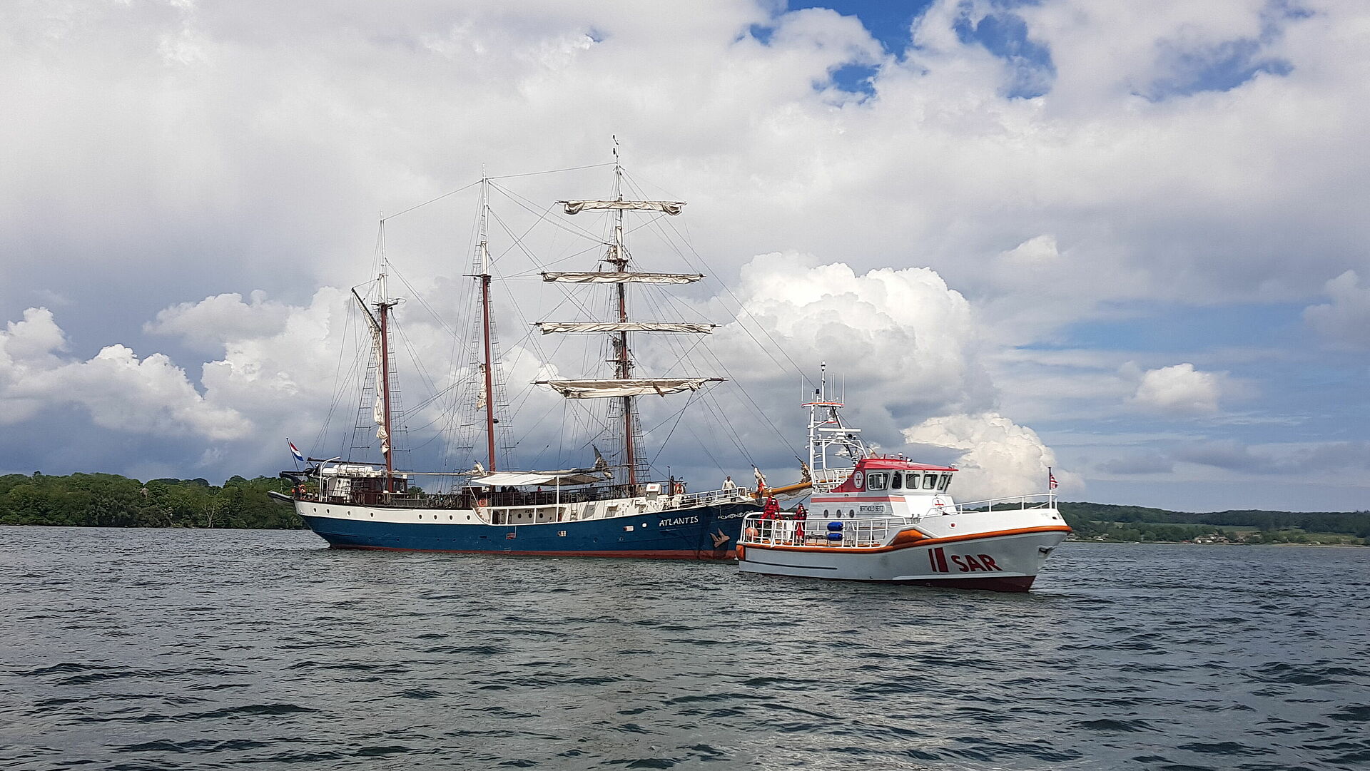 Ein Seenotrettungskreuzer auf der Ostsee schleppt ein großes Segelschiff frei.
