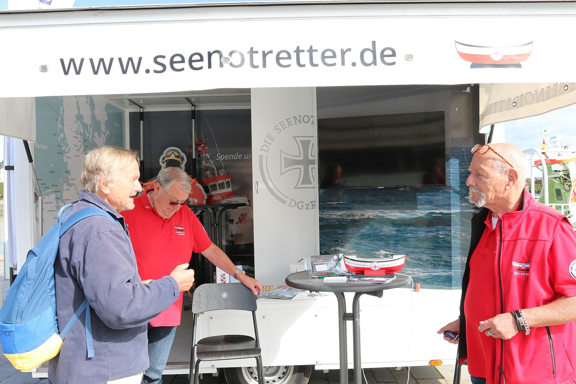 Die Übung stößt im Hafen auf großes Interesse. Christian Teske (r.) und Klaus Ostermann (Mitte), ehrenamtliche Mitarbeiter der DGzRS, informieren am Infomobil.