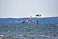 Vor Rügen ist ein Seenotrettungskreuzer und ein Hubschrauber zusehen, die gemeinsam trainieren.