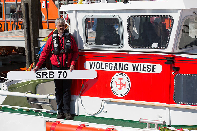 Mann steht mit Namensschild auf einem Seenotrettungsboot