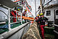 Seenotretter übergeben von Schiff zu Schiff auf See eine orangefarbige Bergungstrage.