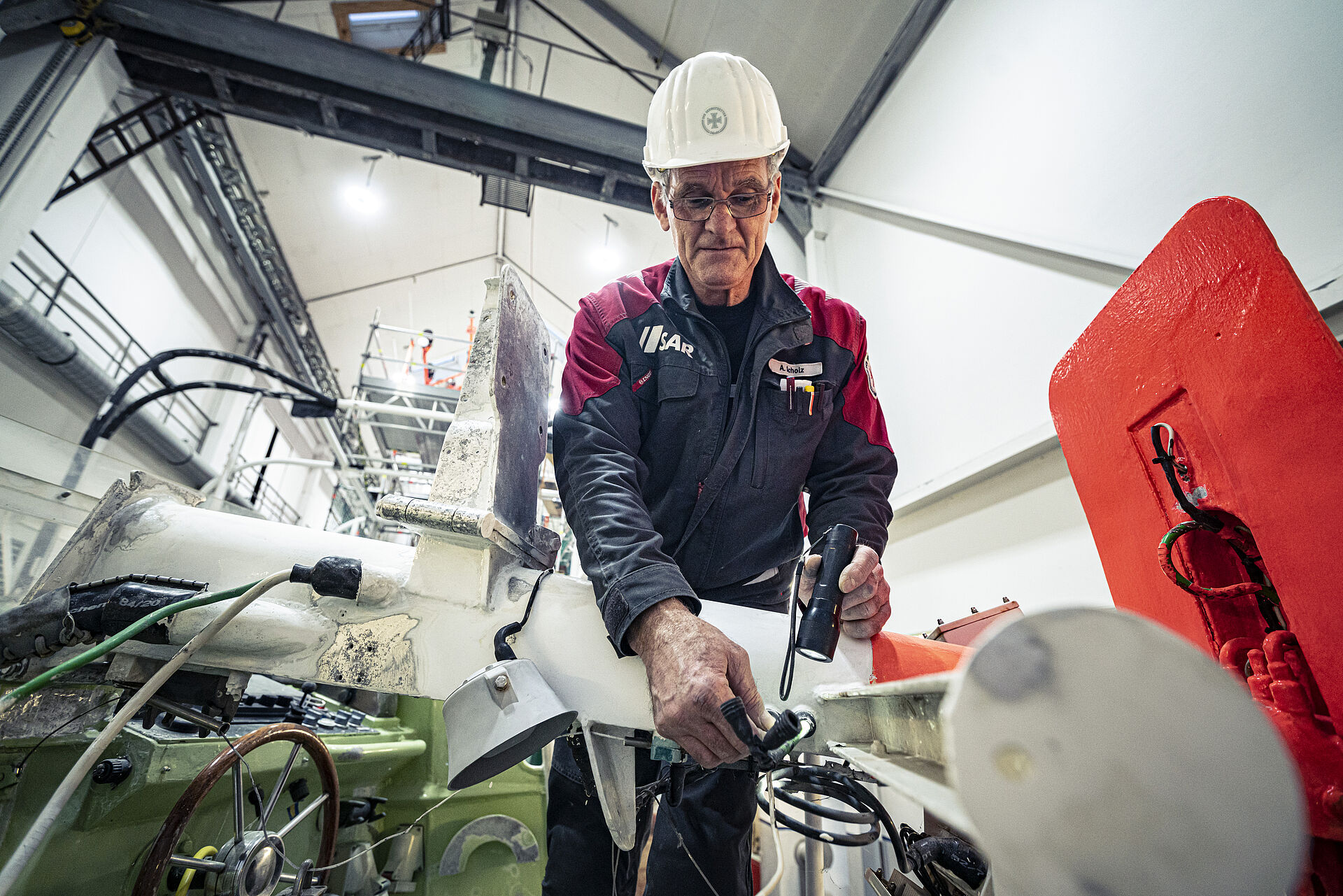 Elektriker Andreas Scholz kümmert sich am Mast der JOHANN FIDI um den richtigen Sitz der Kabel, die er später mit einem Warmschrumpfschlauch abdichtet. Bevor er im Jahr 2000 mit seinem großen Schiffbau-Know-how zu den Seenotrettern wechselte, hat er bei der Schiffs- und Bootswerft Fr. Schweers in Bardenfleth an der Unterweser gearbeitet. Egal, ob der 60-Jährige Kabel zieht, entfernt, sie vor Salzwasser schützt oder auf der Brücke die Kommunikations- und Navigationsanlagen einrichtet, stets weiß er, für wen er sein fachliches Können einsetzt: „Wir machen unsere Arbeit für die Menschen in Not und für unsere Besatzungen, sie alle sollen immer unversehrt wieder an Land zurückkehren.“ Das motiviert ihn täglich aufs Neue, treibt ihn genauso wie seine Kollegen an.