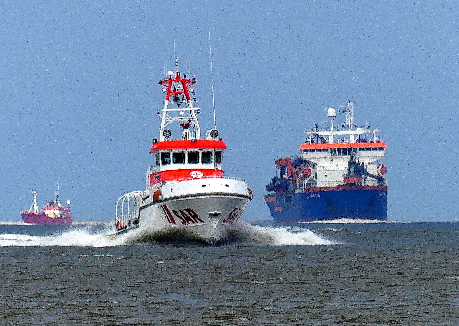 Ein Seenotrettungskreuzer begegnet einem Baggerschiff auf der Nordsee