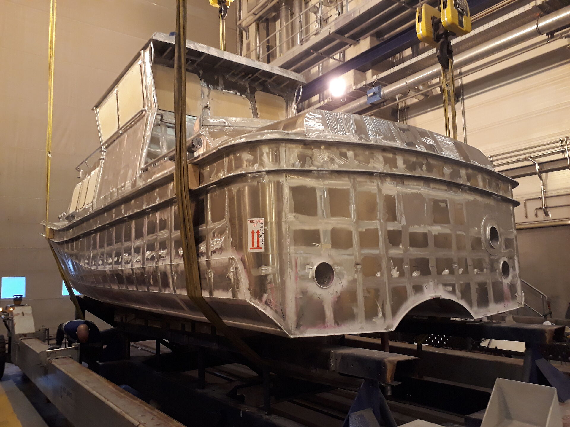 Ansicht des Rohbaus eines Seenotrettungsbootes in euiner Werfthalle. Der unlackierte Körper zeigt blankes Aluminium.