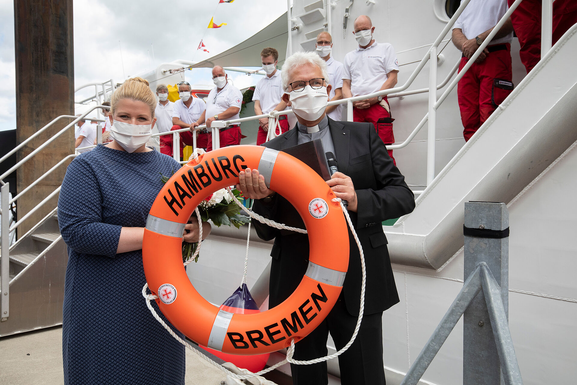 Zwei Personen halten einen Rettungsring mit der Aufschrift HAMBURG BREMEN