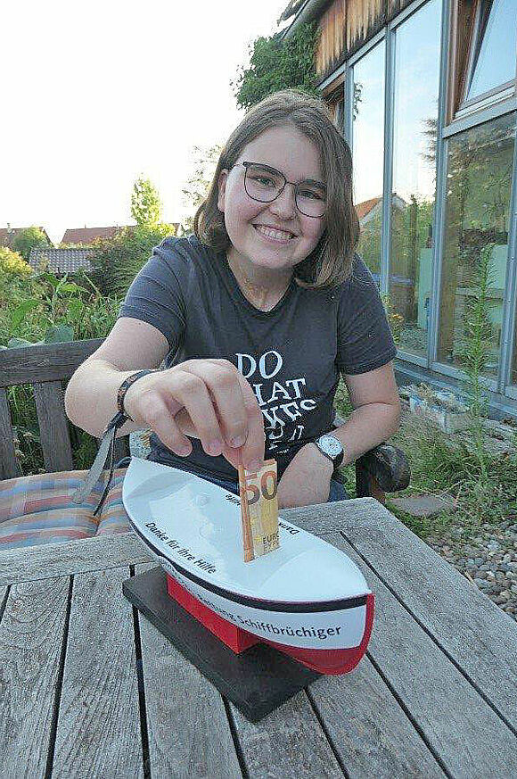 Anna Schuster (15) aus dem baden-württembergischen Althütte steckt einen 50-Euro-Schein durch die Ladeluke eines Sammelschiffchens der Seenotretter.