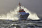 Der Seenotrettungskreuzer HERMANN MARWEDE fährt bei trübem Wetter durch die aufgewühlte Nordsee. Gischt schlägt von den Wellen am Schiff vorbei.