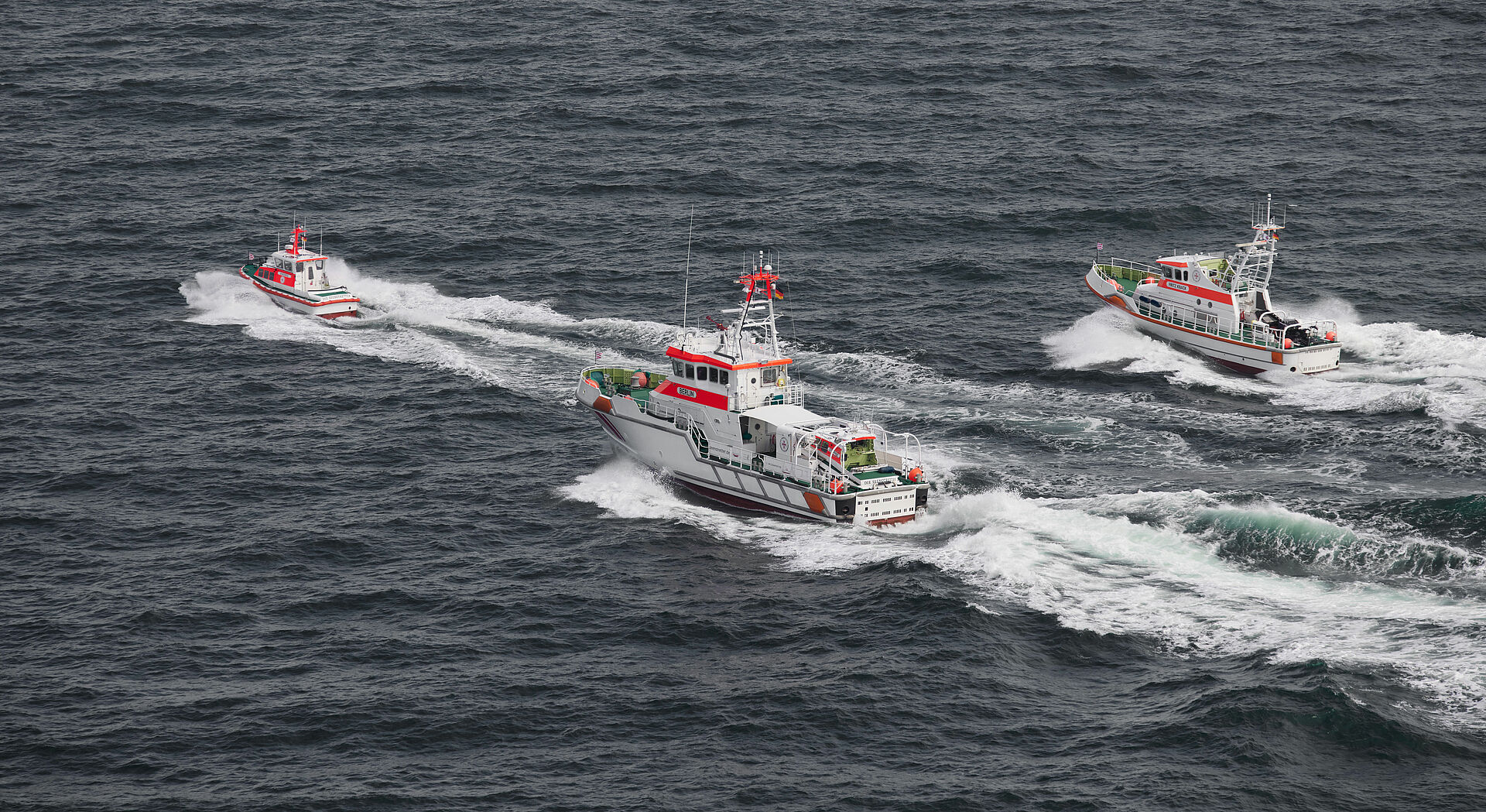 Ein Seenotrettungsboot und zwei Seenotrettungskreuzer fahren in Parallelformation über die Ostsee.