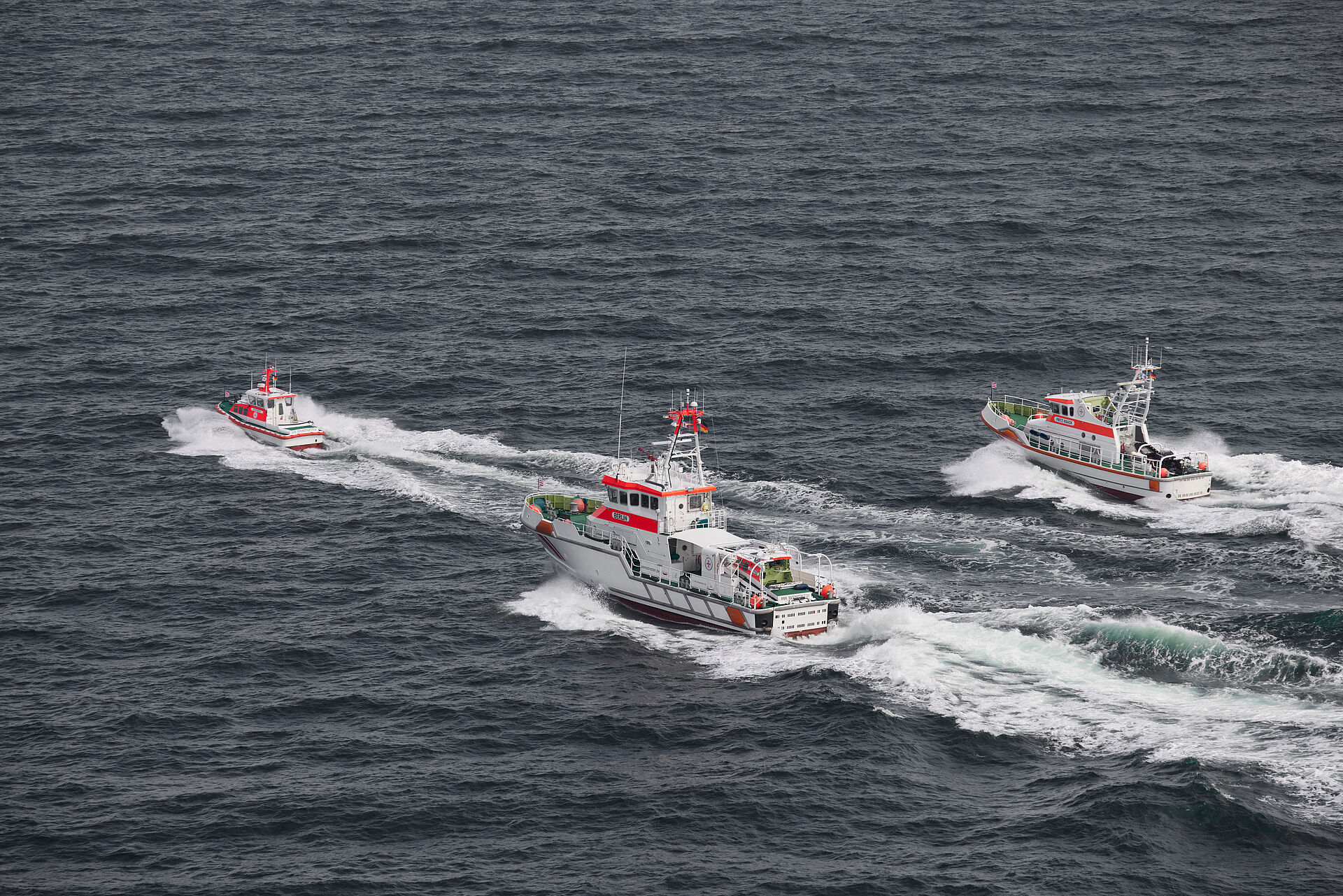 Ein Seenotrettungsboot und zwei Seenotrettungskreuzer fahren in Parallelformation über die Ostsee.
