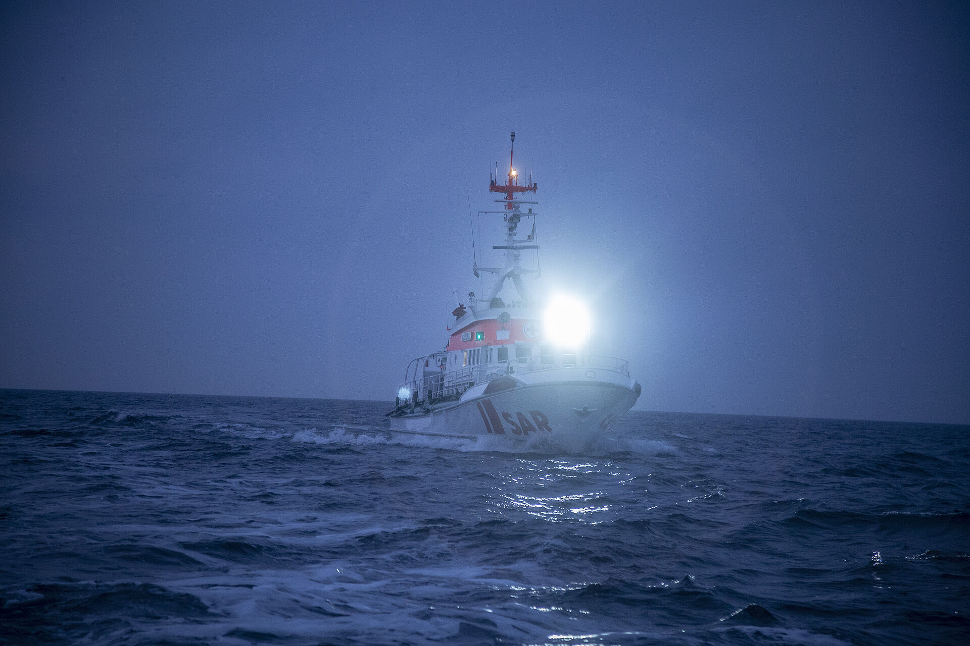 Seenotrettungskreuzer ARKONA strahlt mit großer Leuchte auf das Meer bei nächtlichem Einsatz