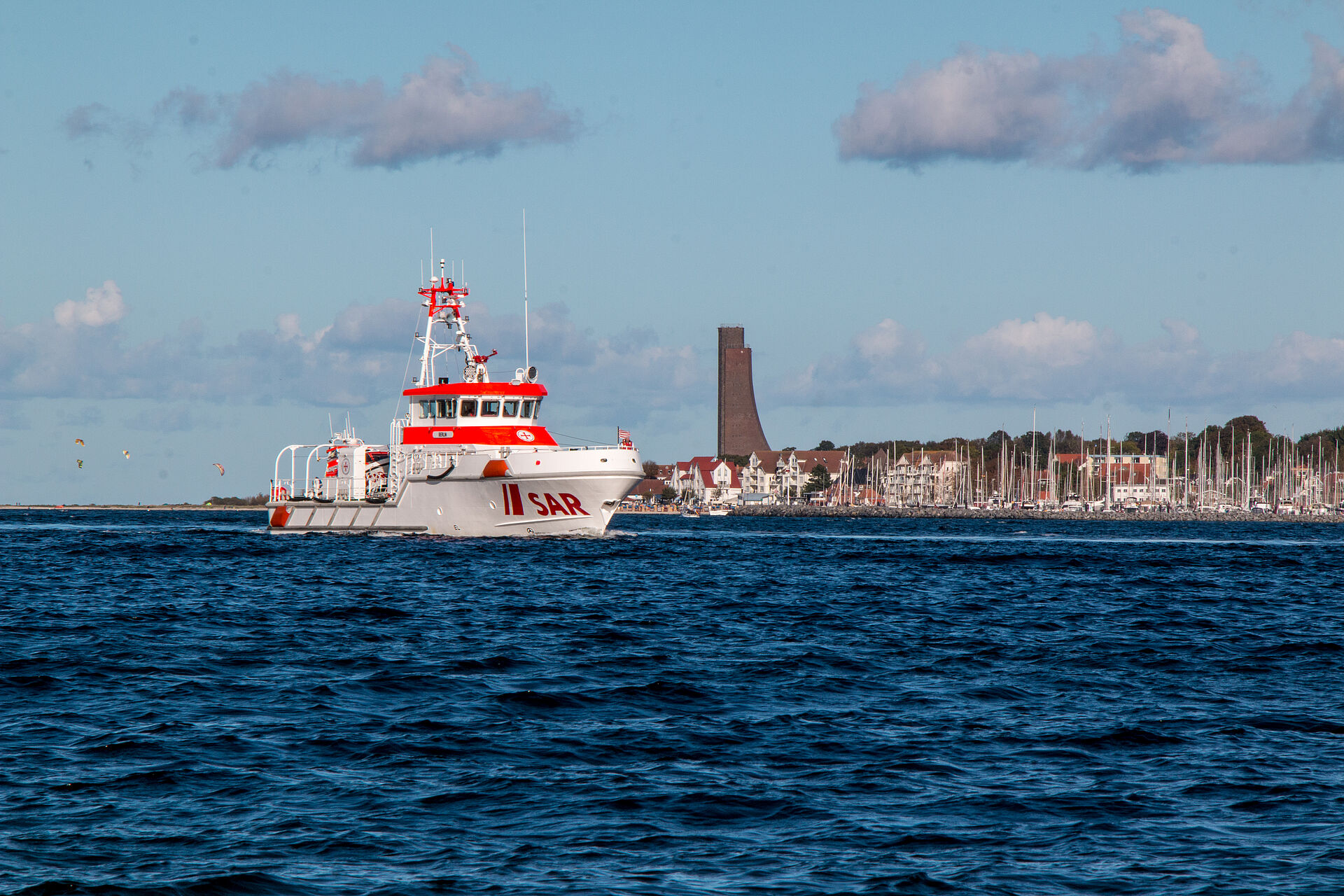 Der Seenotrettungskreuzer BERLIN fährt bei gutem Wetter über die Ostsee bei Laboe. Im Hintergrund ist die markante Silhouette mit dem Marine-Ehrenmal zu sehen.