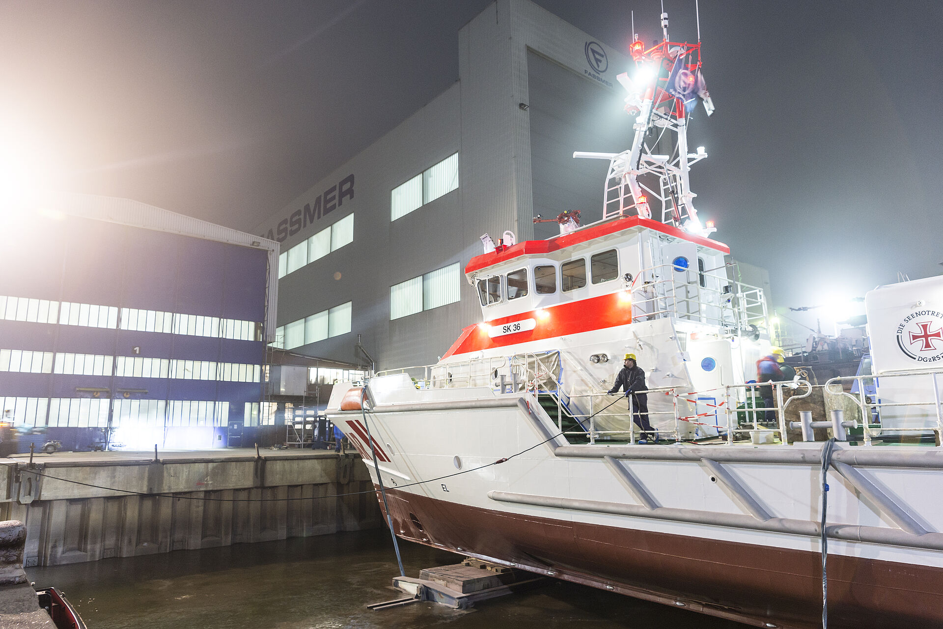 Der Seenotrettungskreuzer BERLIN liegt an einem dunklen Morgen vor der Werfthalle. Scheinwerfer bestrahlen das neue Schiff.