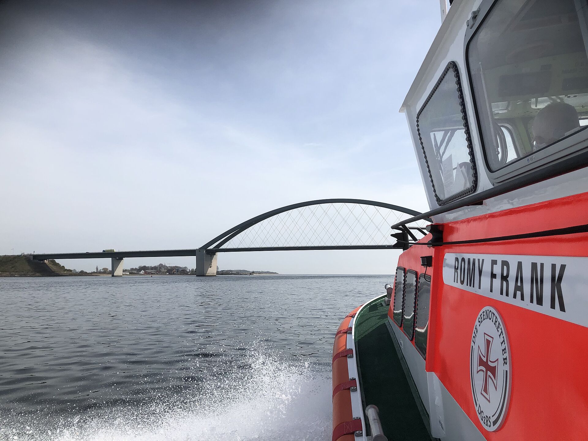Blick vorbei am Aufbau eines Seenotrettungsbootes in Richtung einer großen Brücke über die Ostsee