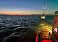 Segelboot im Schlepp eines Seenotrettungskreuzers bei Sonnenaufgang