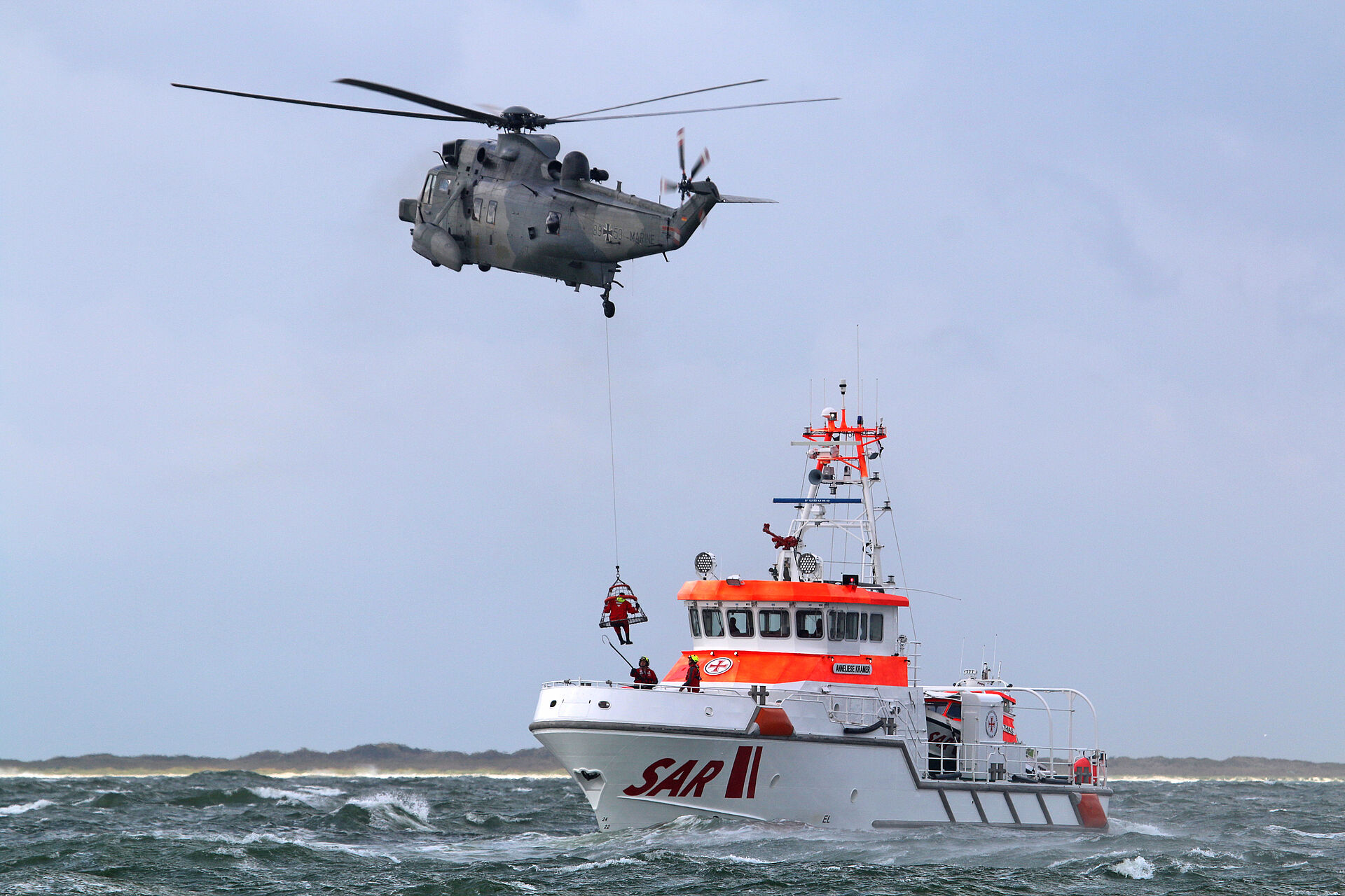 Helikopter fliegt über Seenotrettungskreuzer