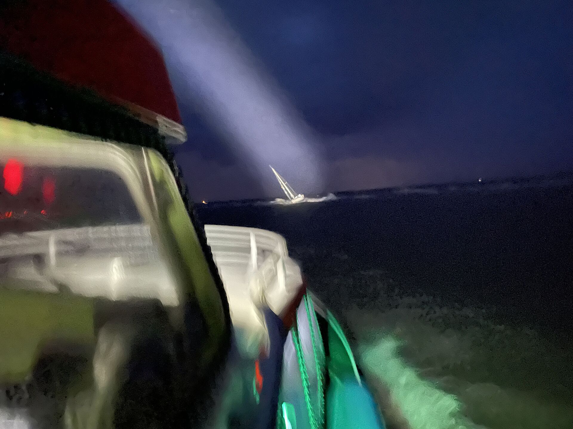 Ein Tochterboot der Seenotretter nähert sich einer Segelyacht, das in einer Brandungszone von Wellen umgeben ist.