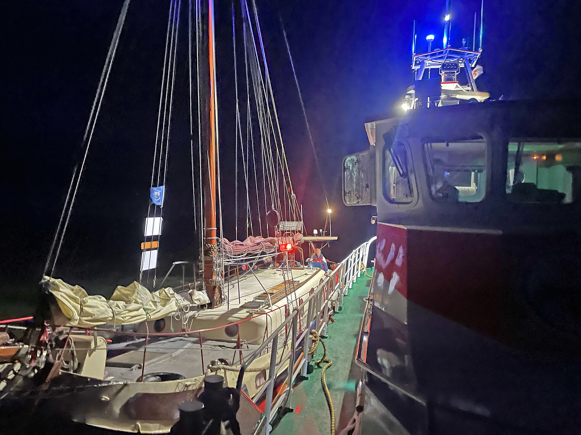 Bei Dunkelheit hat ein Seenotrettungskreuzer längsseits eines historischen Segelschiffes festgemacht.