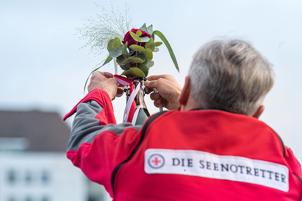 Seenotretter steckt Blumenstrauß in eine Vase bei der Taufe der PUG
