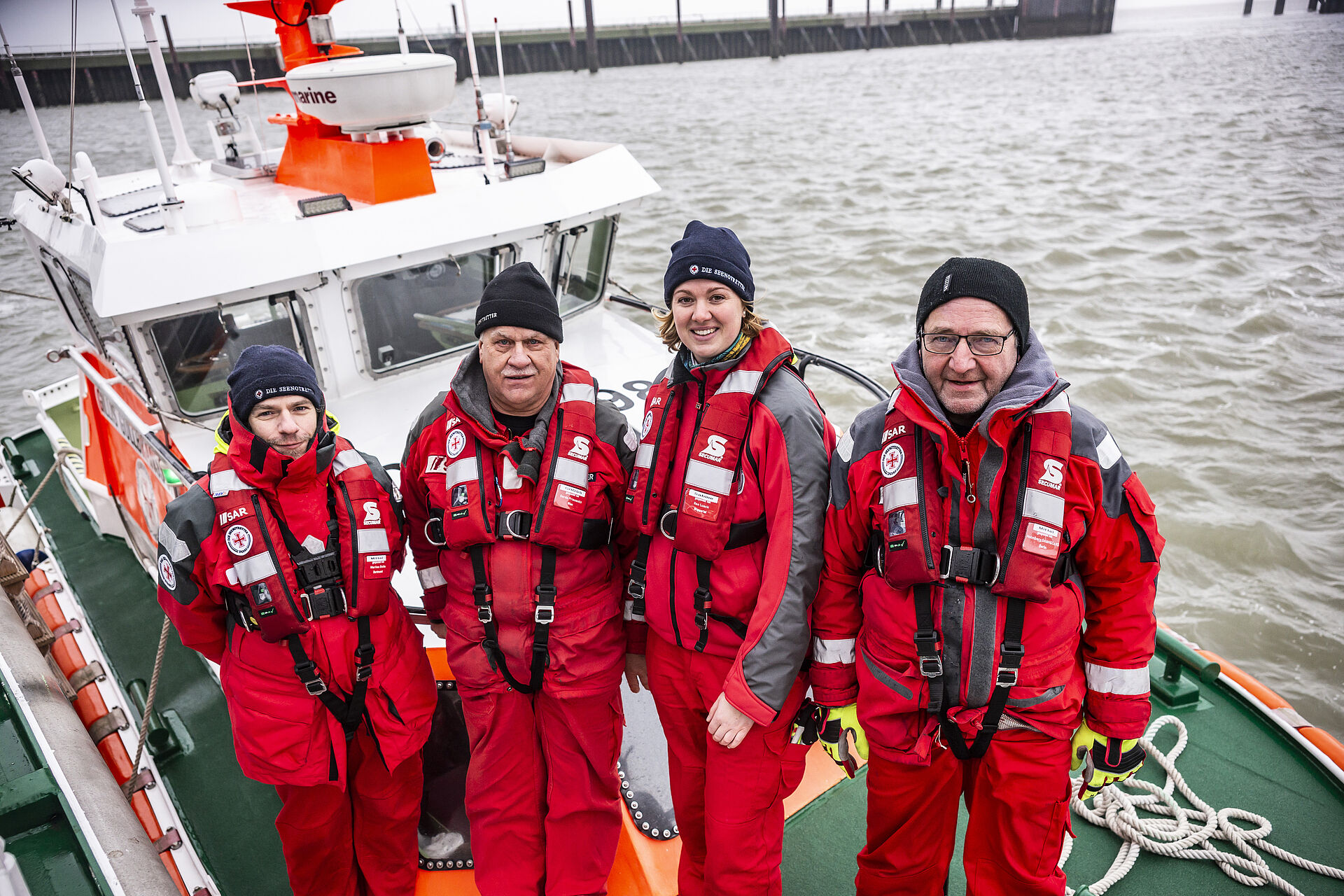 Vier Seenotretter stehen an Deck ihres Seenotrettungsbootes bei kalten Temperaturen