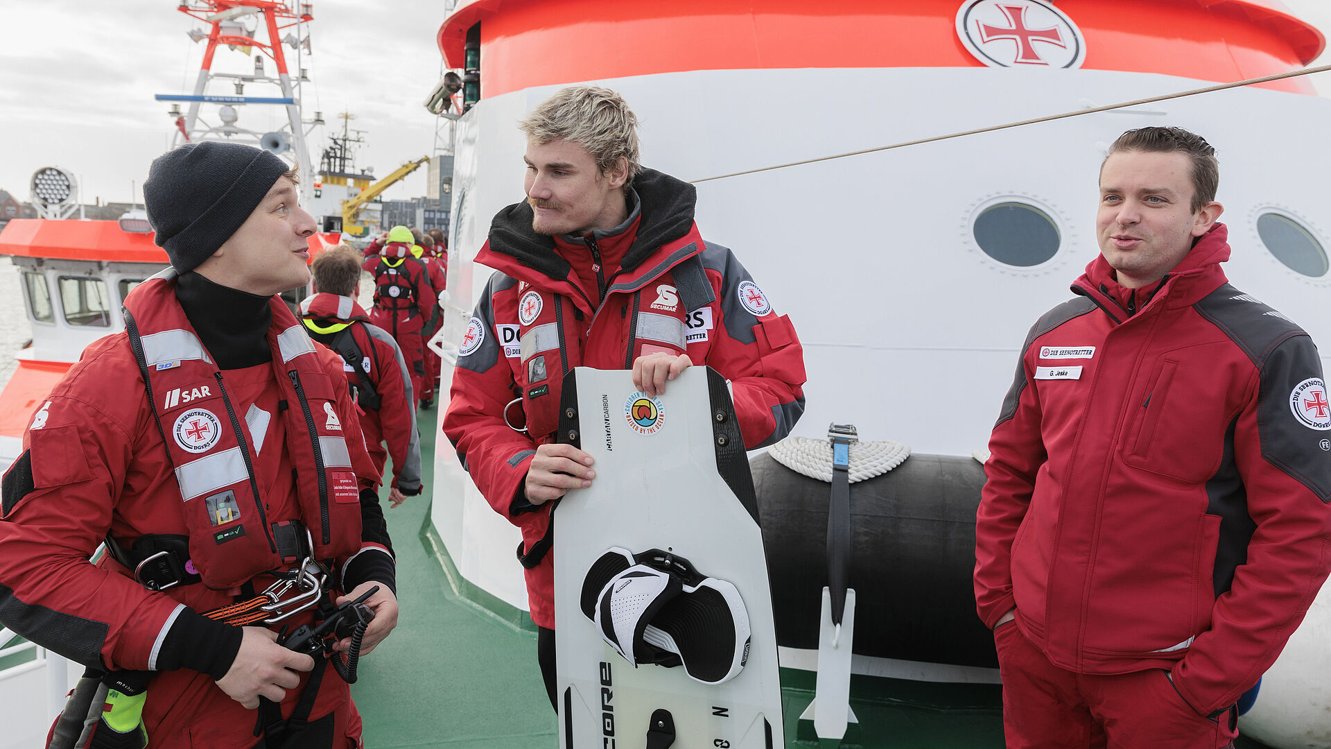 Kiteprofi Linus Erdmann ist an Bord eines Seenotrettungskreuzers im Gespräch mit zwei Seenotrettern.